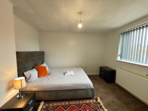 a bedroom with a bed with orange pillows and a window at Spacious Home Near City Centre in Kenton