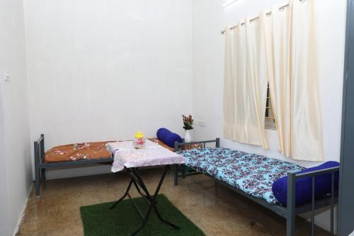 ein Zimmer mit zwei Betten und einem Tisch und einem Fenster in der Unterkunft Garden Home stay Service apartment in Jāmb
