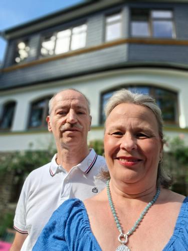 a man and a woman standing in front of a house at ansimali 3 - Treffpunkt Dachgeschosswohnung, Ideal für Familien und Freunde, Gemeinsam wohnen, getrennt träumen, Zwei Schlafzimmer, ein Urlaub mit Spiel und Spaß in Grünhain-Beierfeld