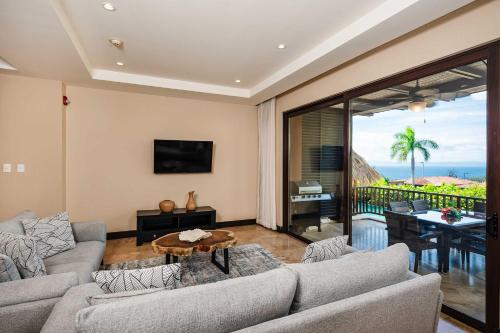 a living room with a couch and a table at Rooftop Pool & Ocean Views, Sunset BBQ in Ocotal