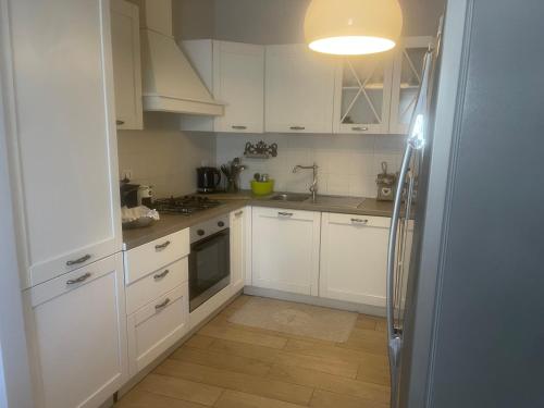 a white kitchen with white cabinets and a refrigerator at Appartamento in Villa in Mondaino