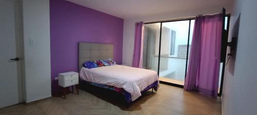 a purple bedroom with a bed and a window at Friendly house in Huanchaco