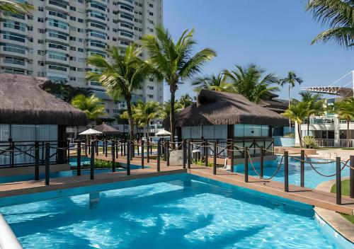 a pool at a resort with palm trees and umbrellas at Bora Bora Resort - Condomínio de Luxo com Lazer na Barra in Rio de Janeiro