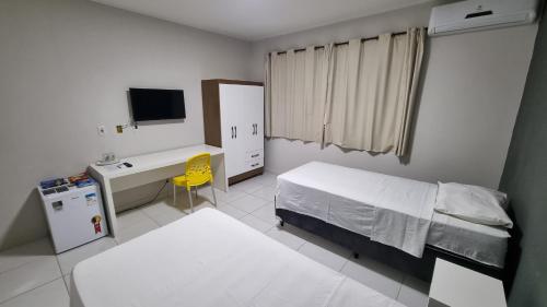 LajesにあるPousada Itaretamaのベッド、机、テレビのある寝室