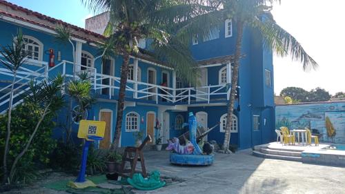 a blue building with palm trees in front of it at Recanto da Alegria suítes in Cabo Frio