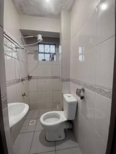 a white bathroom with a toilet and a sink at Opal suites KE - South B in Nairobi