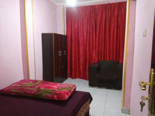 a room with a bed and a red curtain and a chair at Giza Pyramids Hotel in Cairo