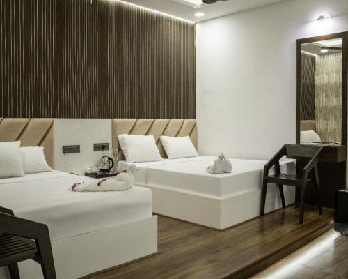 two beds in a room with a mirror and a table at Winners Hill Resorts in Coimbatore