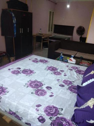 a bed with a blanket with purple roses on it at Giza Pyramids Hotel in Cairo