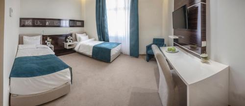 um quarto de hotel com um quarto com uma cama e uma secretária em Theater Hotel Belgrade em Belgrado