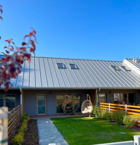 a house with a metal roof and a yard at Pod Lasem Apartamenty in Łukęcin