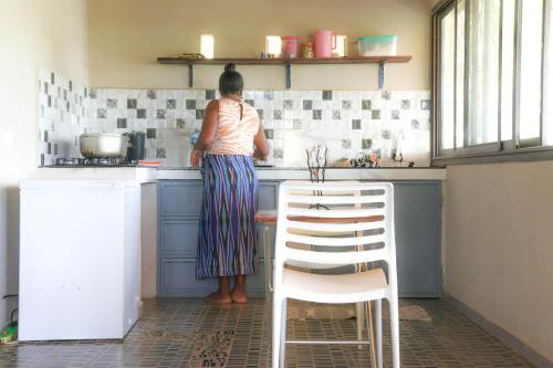 a woman standing in a kitchen preparing food at Maison Bevalavy Vue mer et plage privée à Nosy Be in Nosy Be