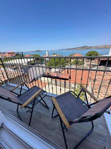 two chairs and a table on a deck with the ocean at aj konukevi müstakil ev dört odalı in Ayvalık