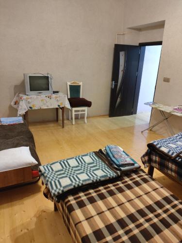ein Zimmer mit mehreren Betten auf einem Holzboden in der Unterkunft Частный дом in Şəki