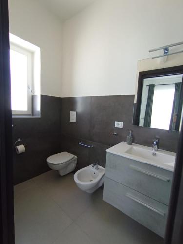 a bathroom with a sink and a toilet and a mirror at Villa Nunzia in Ostuni