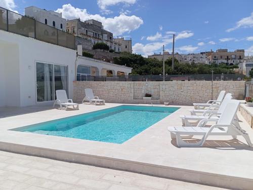 a swimming pool with lounge chairs next to a building at Villa Nunzia in Ostuni