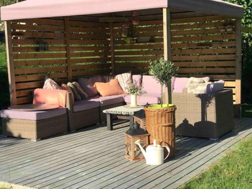 a pergola with couches and a table on a deck at Charming Cottage near Beach & Nature in Sarpsborg