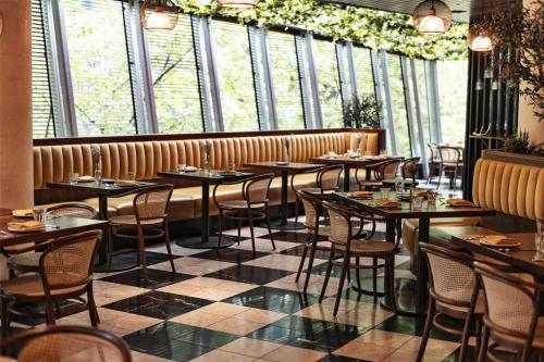 a restaurant with tables and chairs in a room with windows at Hyatt Vancouver Downtown Alberni in Vancouver