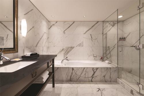 a bathroom with a tub and a glass shower at Hyatt Vancouver Downtown Alberni in Vancouver