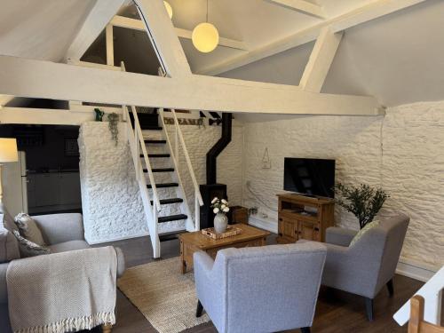 una sala de estar con un loft con una escalera en The Dairy Cotswolds Cottage Farm With Pool, en Lechlade