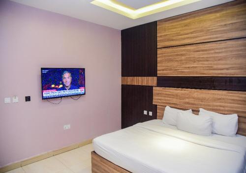 a bedroom with a bed and a tv on the wall at Hotel De Alommah Kubwa Abuja in Abuja