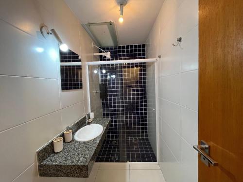 a bathroom with a sink and a black tiled shower at 400m da Praia | Roupa de cama/banho in Pauba