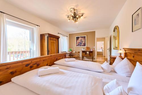 two beds in a large room with a window at Hotel Waldgasthof Buchenhain in Baierbrunn