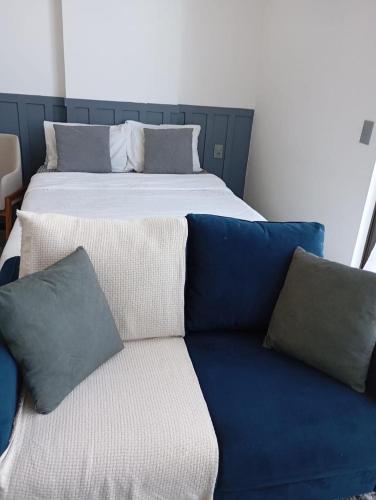 a bed with blue and white pillows and a couch at Apartamento na Cobertura BeiraMar Pajuçara in Maceió