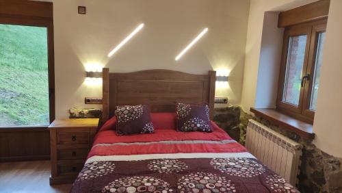 a bedroom with a bed with a red comforter at EL PICO Casa en plena naturaleza con vistas espectaculares in Arredondo