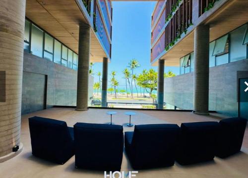 a lobby of a building with chairs and tables at Apartamento na Cobertura BeiraMar Pajuçara in Maceió