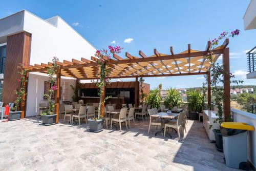 a patio with tables and chairs under a pergola at Uliv Apart Hotel & SPA in Ayvalık
