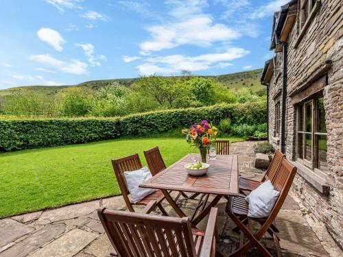 a wooden table with chairs and flowers on a patio at 4 Bed in Longtown 86497 in Llanveynoe