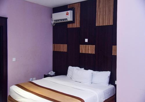 a hotel room with a bed with white sheets at Hotel De Alommah Kubwa Abuja in Abuja