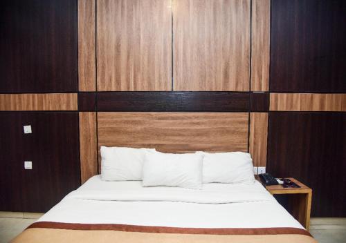 a bedroom with a bed with a wooden wall at Hotel De Alommah Kubwa Abuja in Abuja
