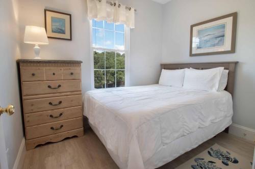 a bedroom with a bed and a dresser and a window at Pier Pleasure in Folly Beach