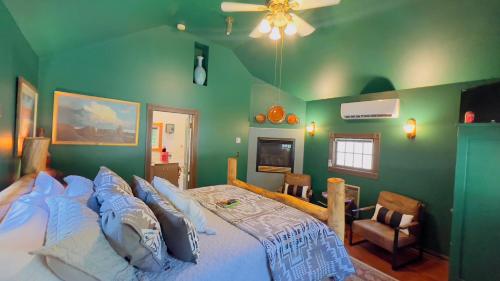 a bedroom with green walls and a bed with blue pillows at Rock Cottage Gardens B&B in Eureka Springs