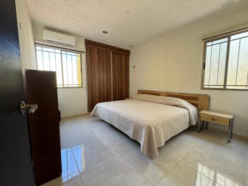 une chambre avec un lit et deux fenêtres dans l'établissement Bonita Casa Vacacional. Punto medio entre ciudad y playa, à Mérida