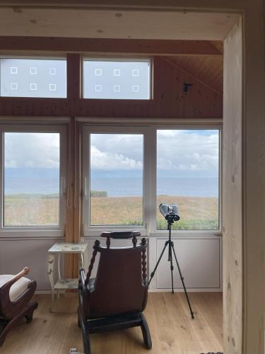 a room with windows with a camera and a chair at Lava House on the Ocean in Arnarstapi