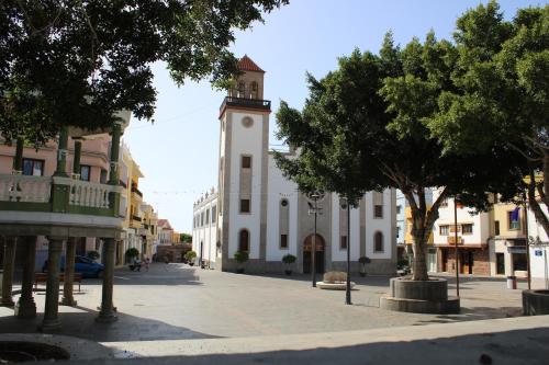 a building with a clock tower in the middle of a street at Casas La Aldea Suites Plaza in La Aldea de San Nicolas