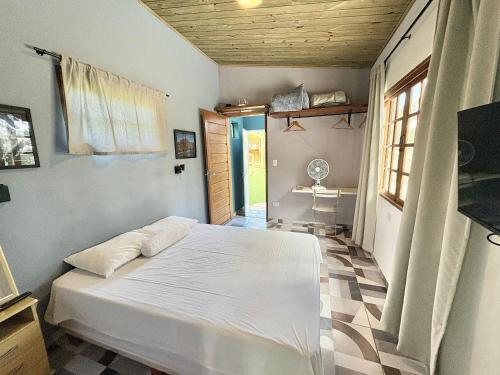 a bedroom with a white bed in a room at Casa Caipira , Refúgio na Floresta Rota do Vinho in São Roque