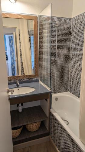 une salle de bain avec un lavabo, une baignoire et un miroir dans l'établissement Appartement rez de jardin 4 à 5 personnes CAP ESTEREL, à Saint-Raphaël