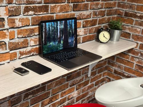a laptop computer sitting on a table next to a brick wall at Affordable Luxury Capsule Bed in Downtown Dubai Near Metro in Dubai