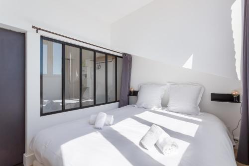 a bedroom with a white bed with a large window at Belfort- Duplex in Lyon