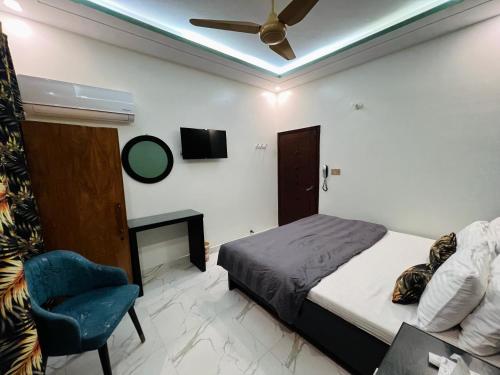 a bedroom with a bed and a chair and a ceiling fan at Karachi Inn in Karachi