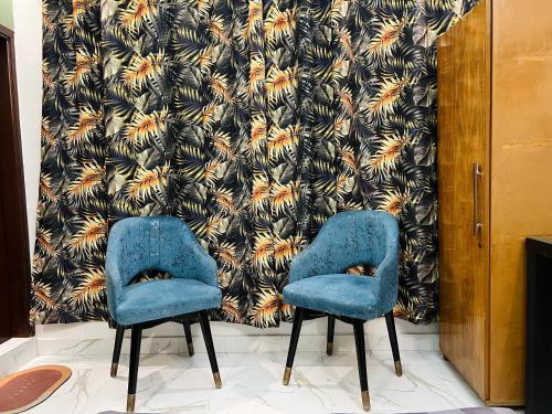two blue chairs in a room with a wallpaper at Karachi Inn in Karachi