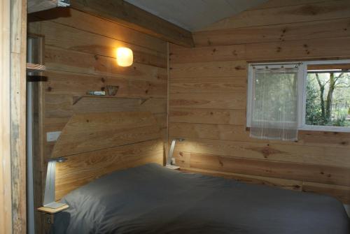 a bedroom with a bed in a log cabin at La Palombière in Saint-Symphorien
