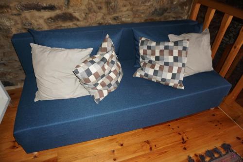 a blue couch with three pillows on it at Casa de Gondramaz - Galeria com Vista Serra in Miranda do Corvo