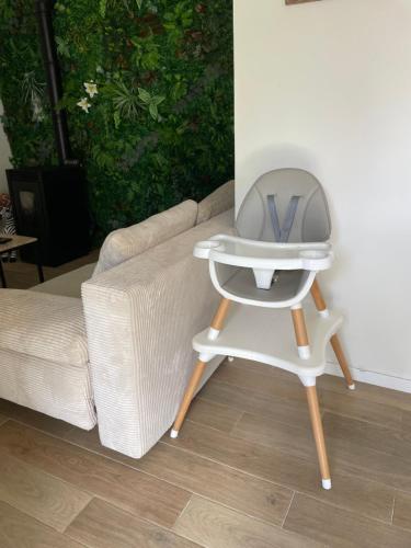 a white high chair sitting next to a couch at La jungle in Saint-Nicolas-dʼAliermont