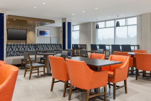 une salle à manger avec des tables et des chaises orange dans l'établissement Holiday Inn Express & Suites Ottawa East-Orleans by IHG, à Ottawa