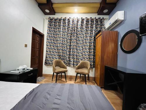 a bedroom with two chairs and a bed and a window at Karachi Inn in Karachi